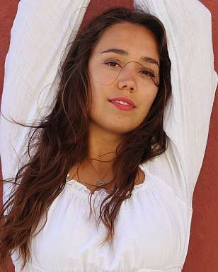 Portrait of Jane in Flames in a white dress against a red wall, Swiss singer-songwriter