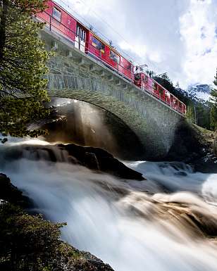 Sunstar Swiss Hotel Collection - Pontresina SBB A red train of the Rhaetian Railway crosses a bridge over a river