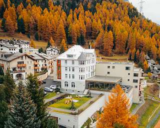 Aussenansicht des Sunstar Hotels Pontresina mit historischer Fassade, Gartenanlage und Liegestühlen im Herbst