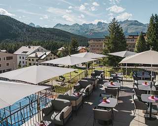 Sun terrace of the Sunstar Hotel Pontresina with seating areas, umbrellas and views of the mountain landscape